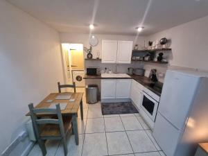 a kitchen with a table and a white refrigerator at Cosy Moat House Cottage #6 in Pembroke