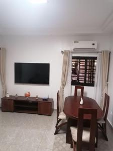 a living room with a table and a television at Appartement meublé 2 pièces rez de chaussée, Résidence Nehemie in Abidjan