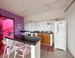 a kitchen with a white refrigerator and purple walls at Vila Real Apartamentos in Itacaré