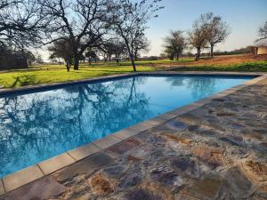 una imagen de una piscina en un parque con árboles en Makua Bush Hotel en Mochudi