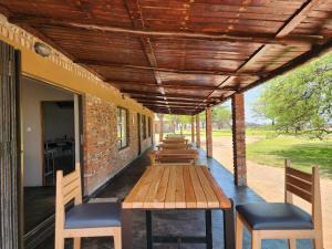 Makua Bush Hotel في Mochudi: شرفة مع طاولة وكراسي خشبية عليها
