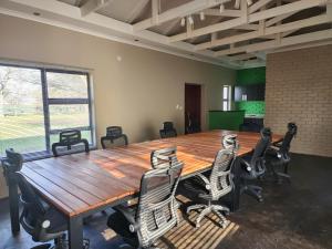 Makua Bush Hotel في Mochudi: قاعة اجتماعات مع طاولة وكراسي خشبية كبيرة