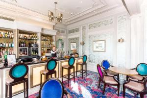 a woman standing at a bar in a room with chairs at Best Western Clifton Hotel in Folkestone