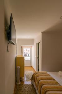una camera da letto con un letto e una televisione su una parete di Suites Bambu a Setúbal Altre 33 foto
