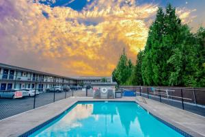 a swimming pool in a parking lot with a sunset at Motel 6-Salem, OR - Expo Center in Salem