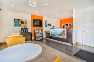Habitación con mesa, TV y paredes de color naranja. en Motel 6-Salem, OR - Expo Center, en Salem
