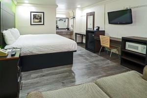 Habitación de hotel con cama, escritorio y TV. en Rodeway Inn San Antonio Lackland AFB - SeaWorld en San Antonio