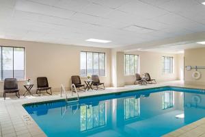 a pool in a hotel with chairs and a table at Comfort Inn & Suites Greenville Near Convention Center in Greenville
