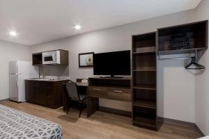 a bedroom with a desk with a computer and a tv at WoodSpring Suites Chandler Airport in Chandler