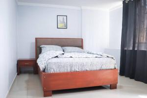 1 dormitorio con 1 cama con marco de madera en MARIBART RESIDENCE - Électricité inclus, Forage, en Yaoundé