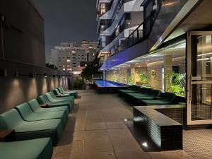 a rooftop bar with green chairs and a building at Apartamento de luxo em Jardins, Oscar Freire in Sao Paulo
