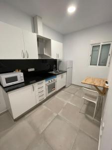 eine Küche mit weißen Schränken und einem Tisch darin in der Unterkunft La Meridian II in Barcelona