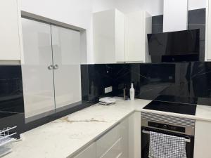 eine Küche mit weißen Schränken und schwarzen Fliesen in der Unterkunft La Meridian II in Barcelona