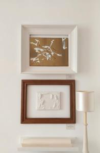 two framed pictures on a wall next to a lamp at Gallery Apartment Bielefeld in Bielefeld