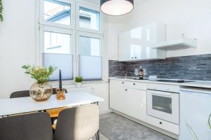 a kitchen with white cabinets and a table with chairs at FourSolos Apartment in Central Essen in Essen