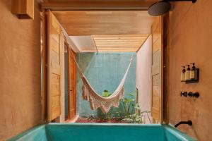 a bath tub with a hammock in a room at Hotel Materia in Oaxaca City
