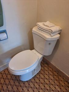 a bathroom with a white toilet with towels on top at Garden motel in Redwood City