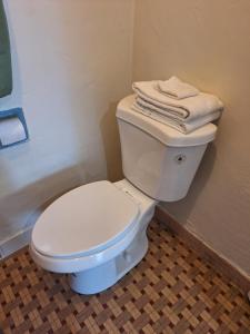 a bathroom with a white toilet with towels on top at Garden motel in Redwood City