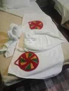 NeNeKaTo Nubian House في أسوان: منشفتان بيض على سرير مع اللون الأحمر والأخضر