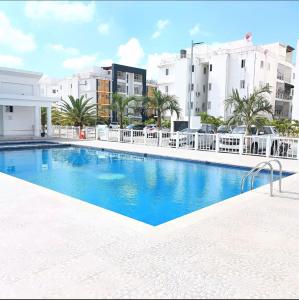 a large blue swimming pool with white fences and buildings at Hermoso residencial con piscina licey al medio in Licey al Medio