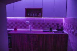 - une cuisine avec un évier et un éclairage violet dans l'établissement Sunny Paradise, à Vrnjačka Banja