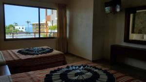 two beds in a room with a window at Aurora Resort in Rincon de Guayabitos