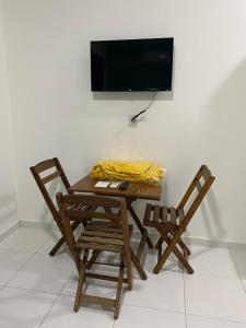a table with two chairs and a television on a wall at Dunas Flat in Galinhos