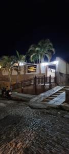 ein Gebäude mit einem Zaun und Palmen in der Nacht in der Unterkunft Jardim Do Eden Piri in Pirenópolis