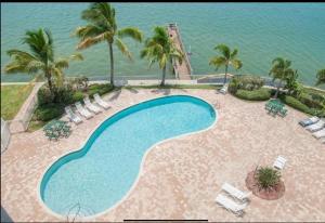 a swimming pool with chairs and the ocean in the background at Boca Ciega Resort in St. Petersburg