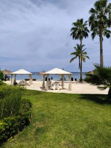 una playa con sombrillas, palmeras y el océano en Playa Escondida: Confort y relax en el Caribe, en María Grande