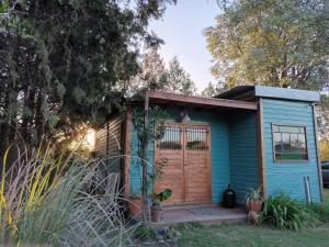 a blue tiny house with a wooden door at Las Nativas de Areco in San Antonio de Areco