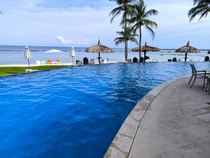 una piscina junto a la playa con sombrillas en Playa Escondida: Confort y relax en el Caribe, en María Grande