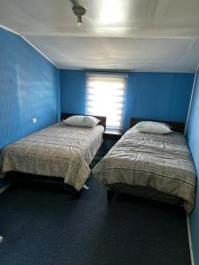 two beds in a room with blue walls at Hospedaje Sra Jenny in Puerto Montt