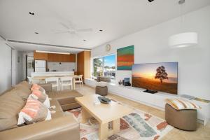 a living room with a couch and a tv on a wall at Unit 105 Plantation Resort Rainbow Beach in Rainbow Beach