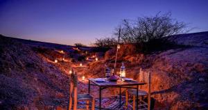 a table with chairs and lights on a hill at The magic of camping in Marrakech