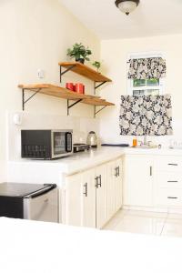 a kitchen with white cabinets and a black microwave at La Maison 29 in Roseau