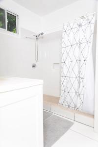 a white bathroom with a shower and a white sink at La Maison 29 in Roseau