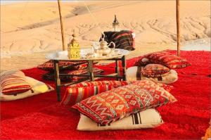 a group of pillows and a table in the desert at The magic of camping in Marrakech