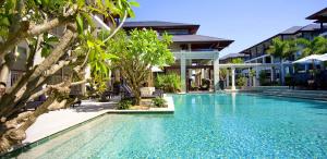 a swimming pool in front of a building with trees at 238 Santai - 2nd Floor King Studio Apartment by uHoliday in Casuarina +2 photos