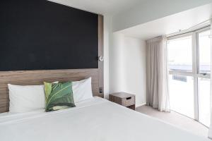 a bedroom with a large white bed with a large window at Mercure Wellington Central City Hotel and Apartments in Wellington