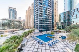 an outdoor pool with chairs and palm trees and buildings at Key View - Bay Central West in Dubai