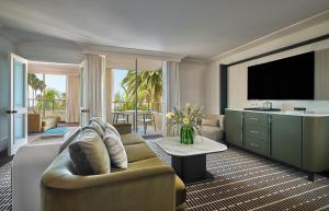 a living room with a couch and a flat screen tv at Pendry Newport Beach in Newport Beach