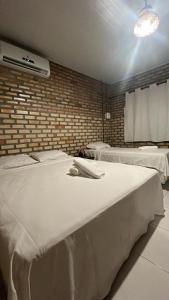 a bedroom with two beds and a brick wall at Villa Arpoador in Tutóia