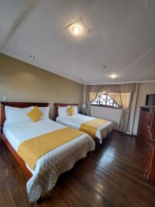 a bedroom with two beds and a window at Hotel Coronel in Cuenca