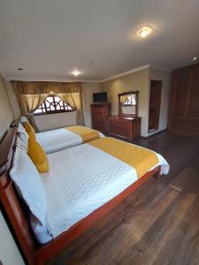 a bedroom with a large bed and two windows at Hotel Coronel in Cuenca