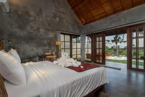 een slaapkamer met een groot bed in een kamer met ramen bij Ubud Luwih Nature Retreat in Ubud