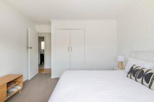 Un dormitorio blanco con una cama grande y una mesa en Quiet & Private with city access and free wifi en Melbourne