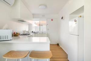 uma cozinha com balcões brancos e um frigorífico branco em Quiet & Private with city access and free wifi em Melbourne