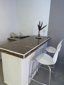a kitchen with a counter and two white chairs at Apartamentos Cupules in Mérida