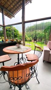 a table and chairs in a room with a large window at Recanto Tereza Dias in Lagoinha